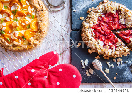 Apricot and strawberry galette placed on wooden table with cooking tools on the side. Apricot and strawberry galette placed on wooden table with cooking tools on the side. 136149958