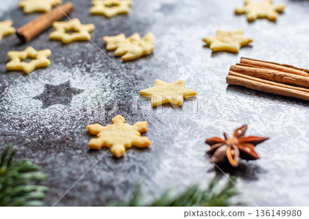 Christmas sweets and cookies in form of christmas tree placed on gray desk with pine cone and branch on the side. Winter and christmas decorations, cinnamon, sugar and star anise. 136149980