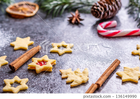 Christmas sweets and cookies in form of christmas tree placed on gray desk with pine cone and branch on the side. Winter and christmas decorations, cinnamon, sugar and star anise. Christmas sweets and cookies in form of christmas tree placed on gray desk with pine cone and branch on the side. Winter and christmas decorations, cinnamon, sugar and star anise. 136149990