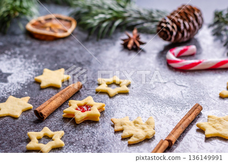Christmas sweets and cookies in form of christmas tree placed on gray desk with pine cone and branch on the side. Winter and christmas decorations, cinnamon, sugar and star anise. Christmas sweets and cookies in form of christmas tree placed on gray desk with pine cone and branch on the side. Winter and christmas decorations, cinnamon, sugar and star anise. 136149991