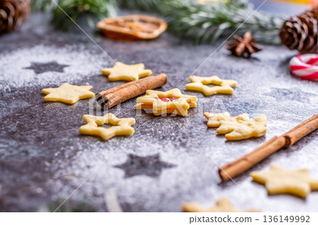 Christmas sweets and cookies in form of christmas tree placed on gray desk with pine cone and branch on the side. Winter and christmas decorations, cinnamon, sugar and star anise. Christmas sweets and cookies in form of christmas tree placed on gray desk with pine cone and branch on the side. Winter and christmas decorations, cinnamon, sugar and star anise. 136149992