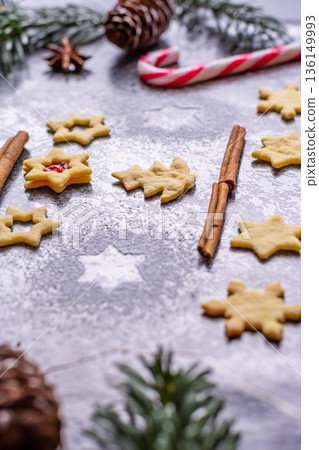 Christmas sweets and cookies in form of christmas tree placed on gray desk with pine cone and branch on the side. Winter and christmas decorations, cinnamon, sugar and star anise. Christmas sweets and cookies in form of christmas tree placed on gray desk with pine cone and branch on the side. Winter and christmas decorations, cinnamon, sugar and star anise. 136149993