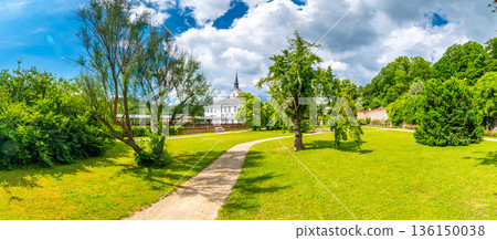 Lysice castle, Czech Republic. Famous baroque castle built in 14th century. Beautiful formal garden, palm trees and flowers. Promenade near the castle. Sunny day, dramatic clouds before storm. Lysice castle, Czech Republic. Famous baroque castle built in 14th century. Beautiful formal garden, palm trees and flowers. Promenade near the castle. Sunny day, dramatic clouds before storm. 136150038