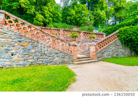 Lysice castle, Czech Republic. Famous baroque castle built in 14th century. Beautiful formal garden, palm trees and flowers. Promenade near the castle. Sunny day, dramatic clouds before storm. 136150050
