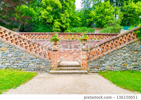 Lysice castle, Czech Republic. Famous baroque castle built in 14th century. Beautiful formal garden, palm trees and flowers. Promenade near the castle. Sunny day, dramatic clouds before storm. 136150051