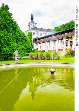 Lysice castle, Czech Republic. Famous baroque castle built in 14th century. Beautiful formal garden, palm trees and flowers. Promenade near the castle. Sunny day, dramatic clouds before storm. Lysice castle, Czech Republic. Famous baroque castle built in 14th century. Beautiful formal garden, palm trees and flowers. Promenade near the castle. Sunny day, dramatic clouds before storm. 136150052