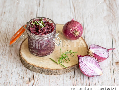 Red onion marmalade placed on wooden trunk with wood texture background. Jam from onion is delicious part of French cuisine. Homemade jam in transparent glass, vibrant colors, soft light. Red onion marmalade placed on wooden trunk with wood texture background. Jam from onion is delicious part of French cuisine. Homemade jam in transparent glass, vibrant colors, soft light. 136150121