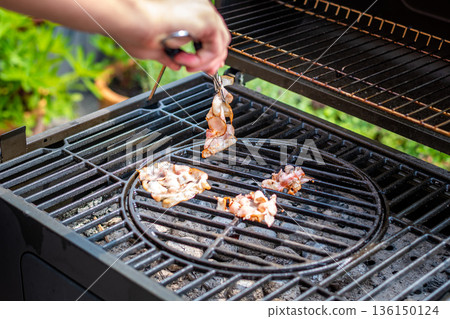 Bacon cooking on the hot grill, preparation of unhealthy food. Bacon cooking on the hot grill, preparation of unhealthy food. 136150124