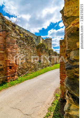 Ruins of Boskovice castle - view of surrounding walls and tower. Summer day, blue sky. Tourism in the Czech Republic - ancient medieval landmark. Ruins of Boskovice castle - view of surrounding walls and tower. Summer day, blue sky. Tourism in the Czech Republic - ancient medieval landmark. 136150255