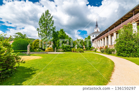 Lysice castle, Czech Republic. Famous baroque castle built in 14th century. Beautiful formal garden, palm trees and flowers. Promenade near the castle. Sunny day, dramatic clouds before storm. 136150297