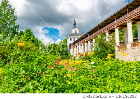 Lysice castle, Czech Republic. Famous baroque castle built in 14th century. Beautiful formal garden, palm trees and flowers. Promenade near the castle. Sunny day, dramatic clouds before storm. 136150298