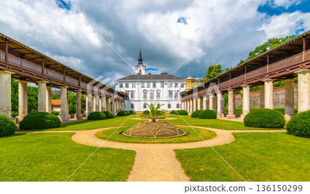 Lysice castle, Czech Republic. Famous baroque castle built in 14th century. Beautiful formal garden, palm trees and flowers. Promenade near the castle. Sunny day, dramatic clouds before storm. 136150299