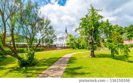 Lysice castle, Czech Republic. Famous baroque castle built in 14th century. Beautiful formal garden, palm trees and flowers. Promenade near the castle. Sunny day, dramatic clouds before storm. Lysice castle, Czech Republic. Famous baroque castle built in 14th century. Beautiful formal garden, palm trees and flowers. Promenade near the castle. Sunny day, dramatic clouds before storm. 136150306