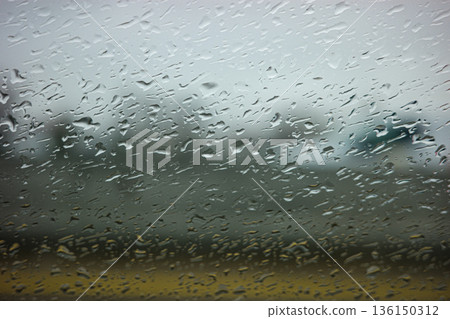 Rain droplets clinging window glass blurring background 136150312