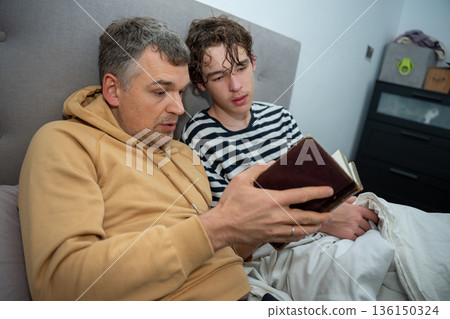 Father and son reading a book together Father and son reading a book together 136150324