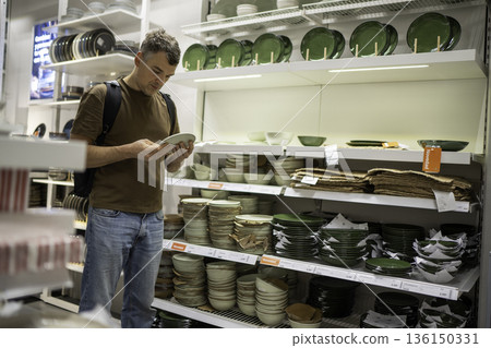Man shopping for dinnerware in store 136150331