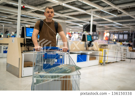 Man shopping with cart in store Man shopping with cart in store 136150338