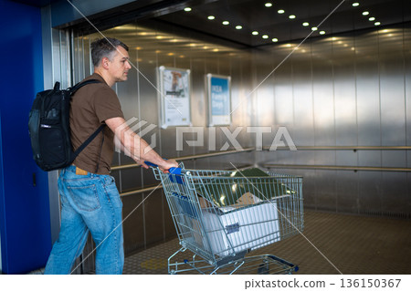 Man pushing shopping cart in elevator Man pushing shopping cart in elevator 136150367