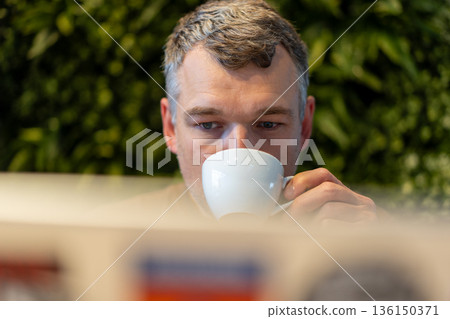 Man drinking coffee in cafe 136150371