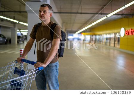 Man pushing shopping cart in parking garage Man pushing shopping cart in parking garage 136150389