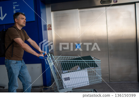 Man with shopping cart by elevator Man with shopping cart by elevator 136150399