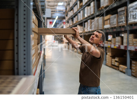 Man selecting box in warehouse aisle Man selecting box in warehouse aisle 136150401