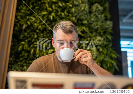 Man enjoying coffee while working on laptop 136150405