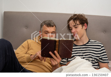 Father and son reading book together 136150407