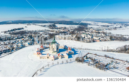 Aerial drone view of Pilgrimage Church of Saint John of Nepomuk, Zdar nad Sazavou, Czech Republic. UNESCO heritage. Ancient monastery at Zelena Hora hill. Winter weather with snow, blue sky. 136150484