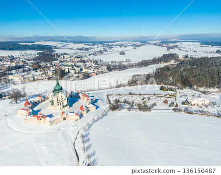 Aerial drone view of Pilgrimage Church of Saint John of Nepomuk, Zdar nad Sazavou, Czech Republic. UNESCO heritage. Ancient monastery at Zelena Hora hill. Winter weather with snow, blue sky. 136150487