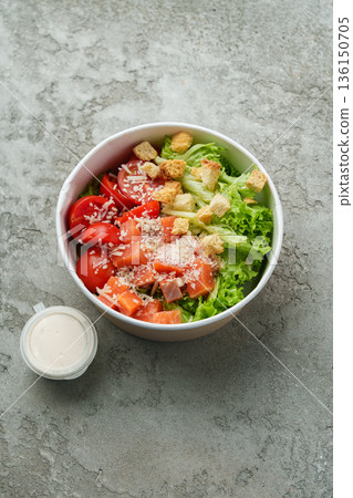 Fresh salad bowl with tomatoes, lettuce, and croutons in a serving container Fresh salad bowl with tomatoes, lettuce, and croutons in a serving container 136150705