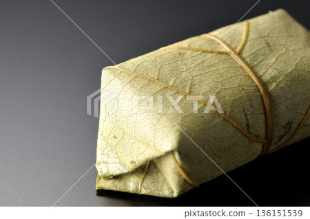 Persimmon leaf sushi photographed against a black background 136151539