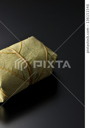 Persimmon leaf sushi photographed against a black background 136151548