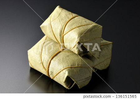 Persimmon leaf sushi photographed against a black background Persimmon leaf sushi photographed against a black background 136151565