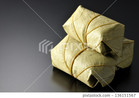 Persimmon leaf sushi photographed against a black background Persimmon leaf sushi photographed against a black background 136151567