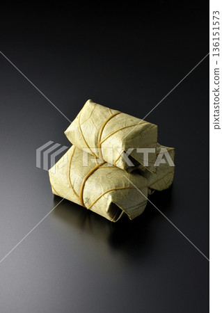 Persimmon leaf sushi photographed against a black background 136151573