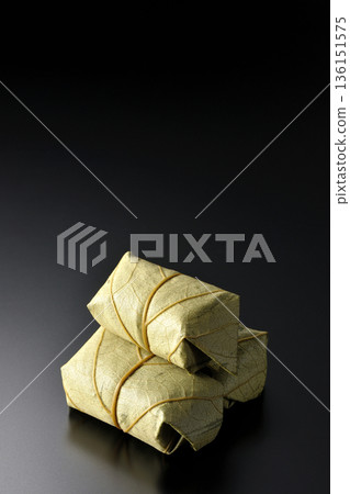 Persimmon leaf sushi photographed against a black background 136151575