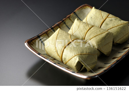 Persimmon leaf sushi photographed against a black background Persimmon leaf sushi photographed against a black background 136151622