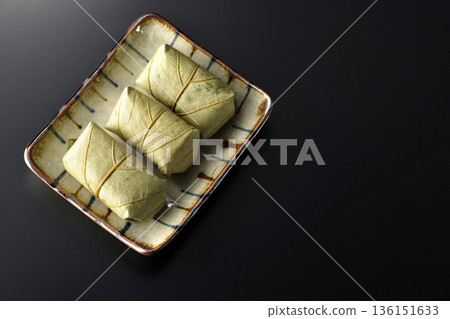 Persimmon leaf sushi photographed against a black background Persimmon leaf sushi photographed against a black background 136151633