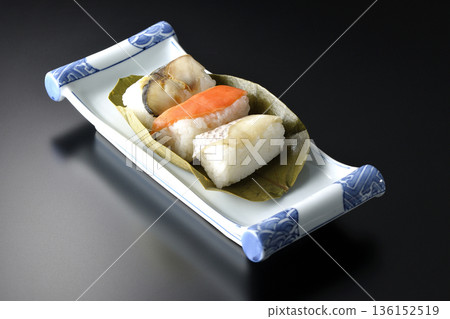 以黑色為背景的柿葉壽司,食材包括鮭魚、鯛魚和鯖魚。 以黑色為背景的柿葉壽司,食材包括鮭魚、鯛魚和鯖魚。 136152519