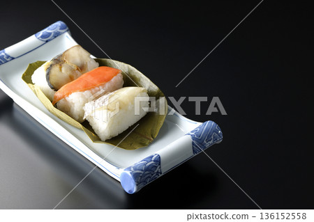 以黑色為背景的柿葉壽司，食材包括鮭魚、鯛魚和鯖魚。 136152558