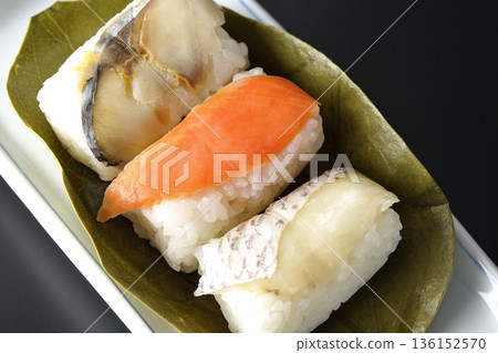 以黑色為背景的柿葉壽司,食材包括鮭魚、鯛魚和鯖魚。 以黑色為背景的柿葉壽司,食材包括鮭魚、鯛魚和鯖魚。 136152570