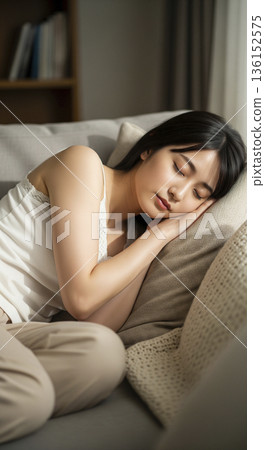 一位日本女性抱著靠墊，舒適地躺在沙發上小憩。 136152575
