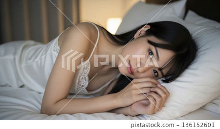 Close-up of a beautiful Japanese woman lying on her side in bed and looking at you 136152601