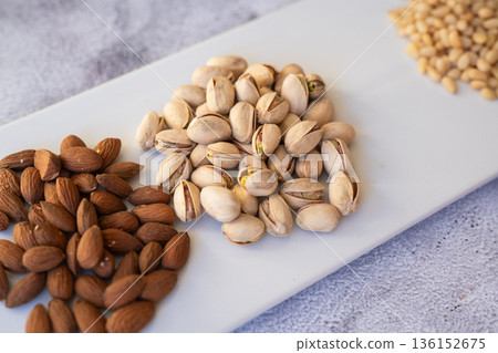 Almonds and pistachios closeup. Artistic presentation of almonds and pistachios emphasizing healthy snacking habits and natural lighting 136152675