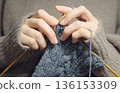 A photo of hands knitting yarn with knitting needles. Knitting, cable knitting, Aran pattern, hobby 136153309