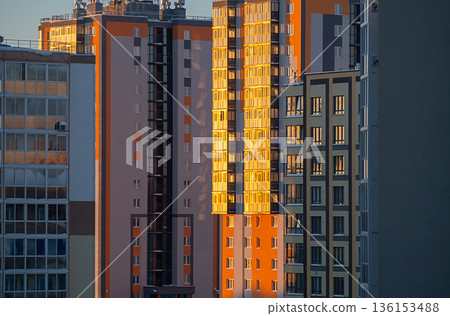 Apartment building exterior with sunny windows at sunset. 136153488