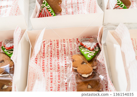 Captured from a close-up perspective, several open holiday cookie gift boxes display an assortment of decorated Christmas cookies, including gingerbread men, stars, and Christmas trees. The carefully Captured from a close-up perspective, several open holiday cookie gift boxes display an assortment of decorated Christmas cookies, including gingerbread men, stars, and Christmas trees. The carefully 136154035