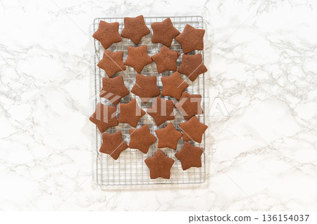 Overhead view of a stack of freshly baked star-shaped chocolate gingerbread cookies on a cooling rack. Overhead view of a stack of freshly baked star-shaped chocolate gingerbread cookies on a cooling rack. 136154037