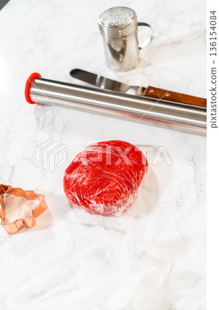 A collection of baking tools, including a rolling pin with red handles, a butter knife with a wooden handle, and a flour sifter, arranged on a marble countertop. These tools are essential for A collection of baking tools, including a rolling pin with red handles, a butter knife with a wooden handle, and a flour sifter, arranged on a marble countertop. These tools are essential for 136154084